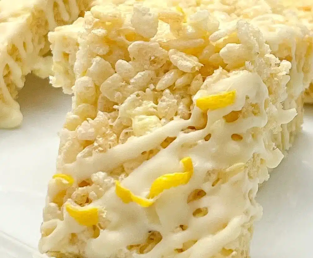 Lemon rice krispy treats stacked on a plate with lemon slices