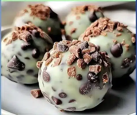 Mint chocolate chip protein balls stacked on a wooden table