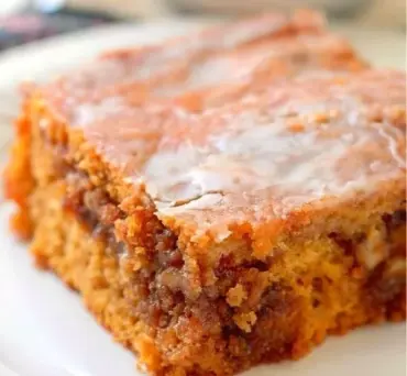 Delicious slice of pumpkin honey bun cake topped with icing and pumpkin seeds