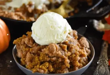 Warm Pumpkin Pie Crisp served in a dish, topped with whipped cream and fall spices.