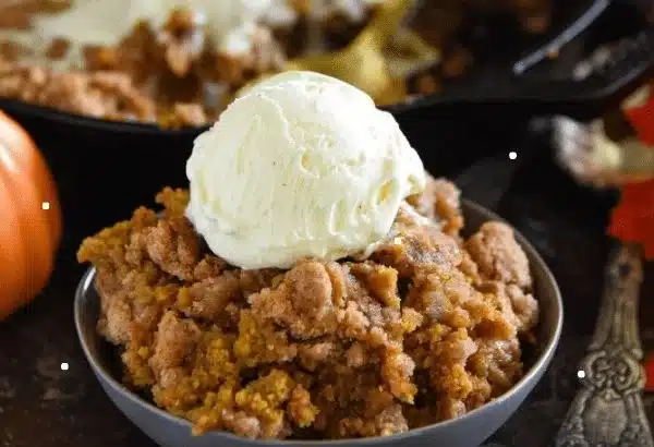 Warm Pumpkin Pie Crisp served in a dish, topped with whipped cream and fall spices.