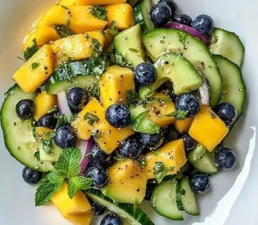 Refreshing Mango Cucumber Salad with blueberries and avocado garnished on a plate